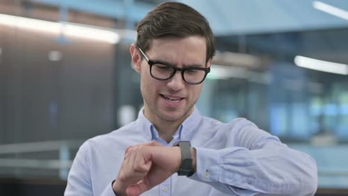 Young Adult Checks Smart Watch in Bright Office