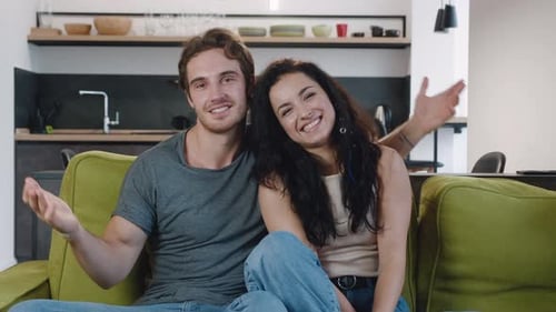 Happy Couple Waving and Talking on Couch