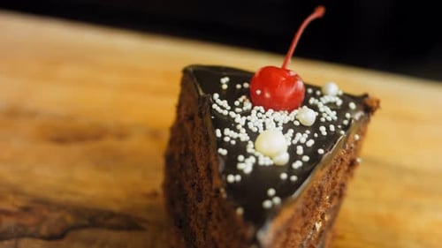 Chocolate Cake Slice with Cherry on Wooden Surface