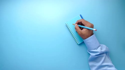 Top View of Man Hand Writing on Notepad.