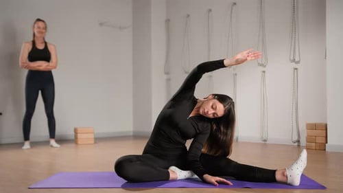 Woman Stretching with Assistance in Bright Yoga Studio