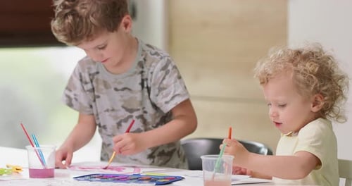Two Children Happily Painting Pictures Indoors