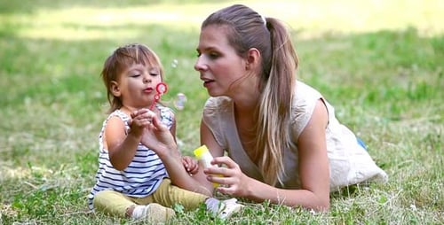 Woman and Child Blowing Bubbles in Park