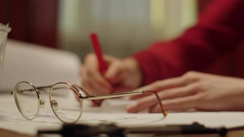 Der junge Designer sitzt und zeichnet mit Lineal und rotem Stift einen Plan und macht ein Designprojekt