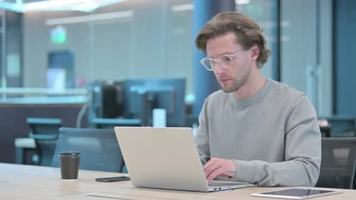 Young Adult Man Working at Laptop in Office