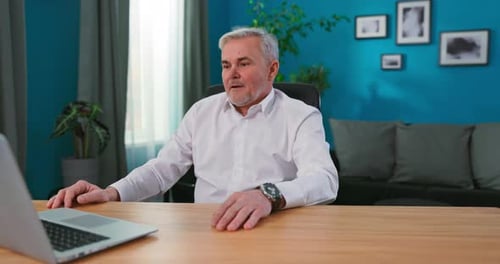 Diretor criativo profissional maduro sentado em sua mesa em seu estúdio de escritório doméstico trabalhando em