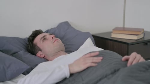 Homme couché dans son lit incapable de dormir