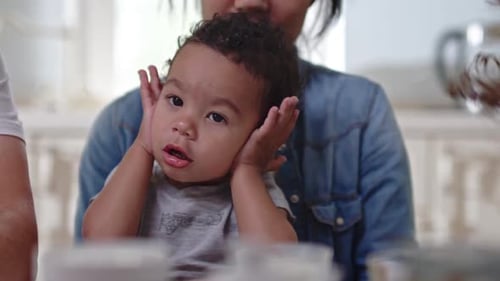 Happy Child on Lap in Kitchen with Family