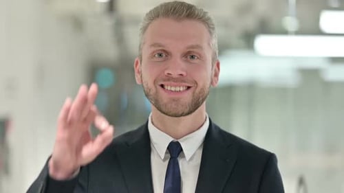 Smiling Man in Suit Gives OK Gesture