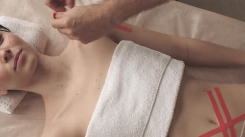 Applying Kinesiology Tape to Young Adult's Shoulder