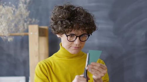 Woman Cutting Green Paper with Scissors Close Up