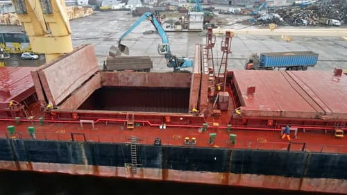 Cargo Ship Loading Material at a Busy Industrial Port