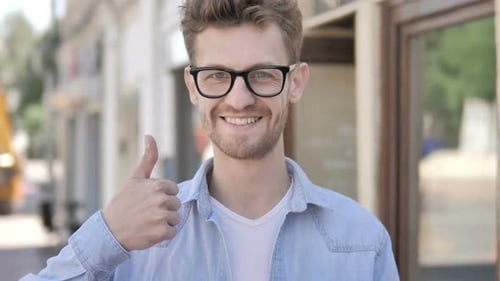 Smiling Man Gives Thumbs Up on City Street
