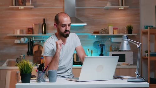 Man Working on Laptop from Kitchen Table