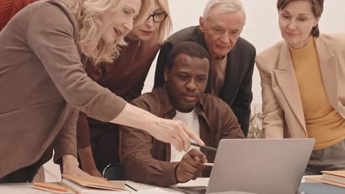 Diverse Team Collaborating Around Laptop in Office