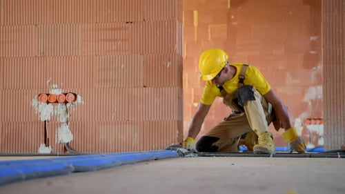 Construction Worker Installs Blue Tubes Indoors