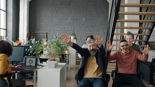 Slow Motion of Crazy Businesspeople Enjoying Office Chair Race Having Fun During Work Break