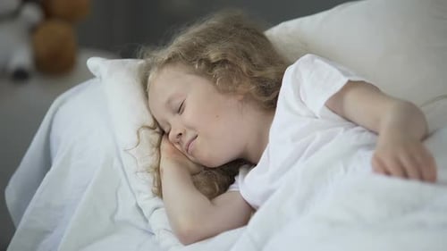 Child Sleeping Soundly in White Bed