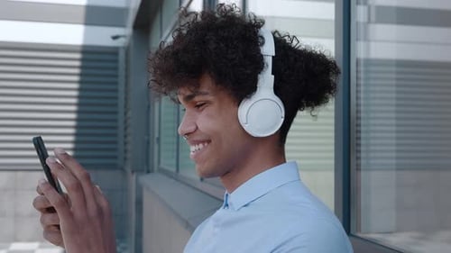 Close Up of Man in Headphones Looking at Smartphone
