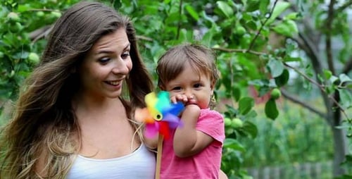 Woman and Child Playing with Pinwheel in Garden