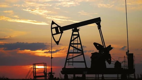 Silhouette Working Oil Pump in Deserted District at Sunset