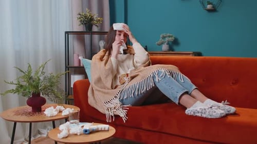 Portrait d'une jeune femme souffrant de froid ou d'allergie en plaid allongé sur un canapé dans le salon à la maison