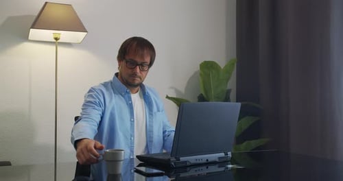 Businessman in Eyeglasses with Laptop Computer Drinking Coffee or Tea at Office. Business, People