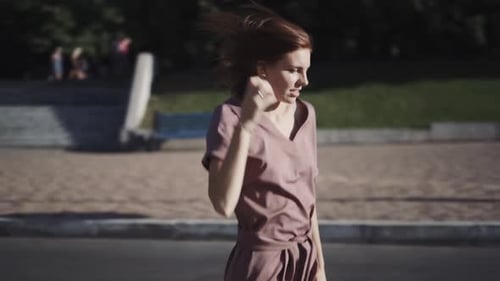 Young Beautiful Redhaired Stylish Woman in a Dress Has a Good Time Outdoors at Sunny Day