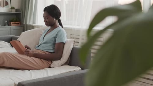 Woman Using Tablet Computer While Relaxing on Sofa
