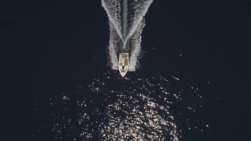 Aerial view of small speed boat with trailing wake on sea.