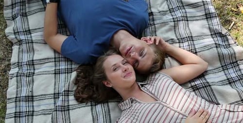Happy Young Couple Lying Together on Plaid Blanket