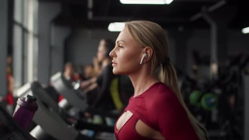 Attractive Woman Athlete in Headphones and Sportswear Performing Cardio Exercises on Treadmill at