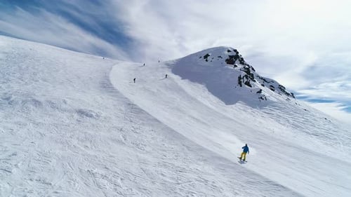 Skiers Descending Snowy Mountain in Winter Aerial