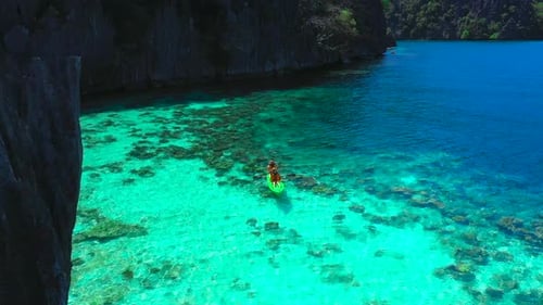 Aerial View Flying Over Amazing Rocks and Tropical Coral Reef Lagoon. Man and Woman Kayak Are