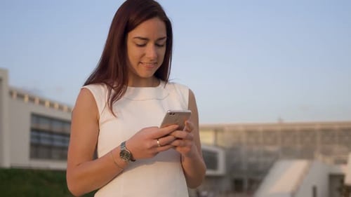 Woman Smiling and Using Smartphone in the City