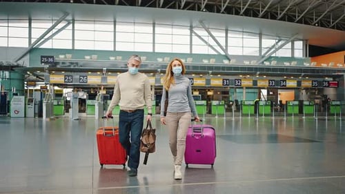 Couple of Confident Middle Aged Travellers Wearing Protective Face Mask Walking with Bright