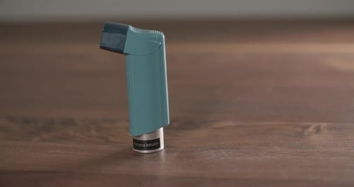 Asthma Inhaler on Table Being Picked Up