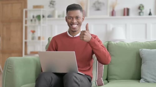 Young Adult Gives Thumbs Up While Using Laptop