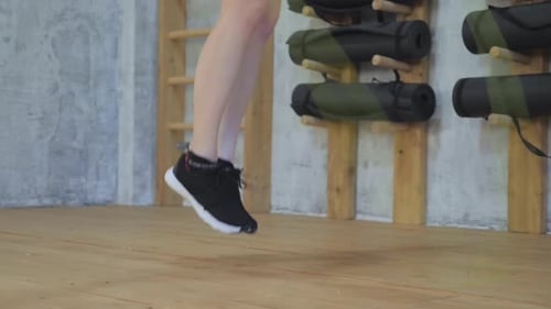 Zeitlupenaufnahme von Frauenfüßen in Sportschuhen beim Seilspringen in einem Indoor-Fitnessstudio