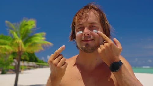 Man Applies Sunscreen on Tropical Beach