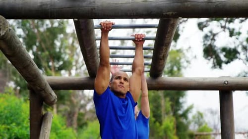 Muscular Man on Monkey Bars in Outdoor Setting