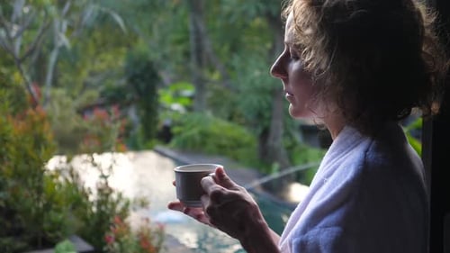 Woman in Robe Looking at View with Cup