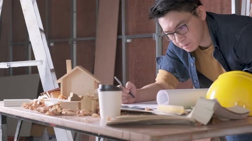 Architect Works on Plans at Desk