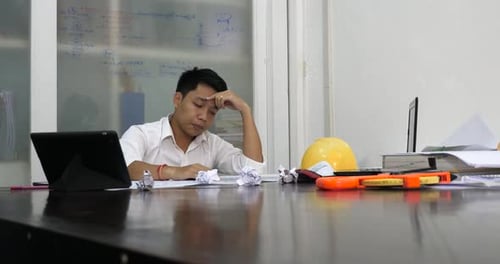 Frustrated Man at a Desk Throws Paper
