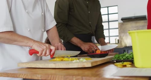 People Slicing Fresh Vegetables in Kitchen Setting