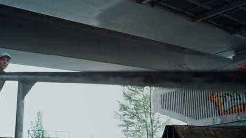 Active Teenager Practicing Jump Trick on Rail on Skate Board in Skatepark
