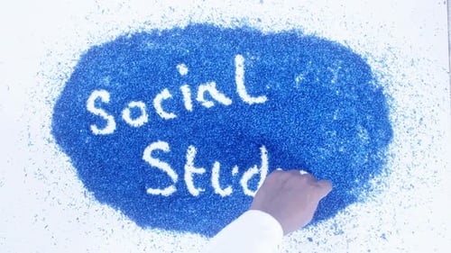 Hand Writes 'Social Studies' in White Powder