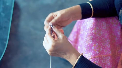 Woman doing knit work tie-up hand work. Close up from above footage of woman's hands knitting with r