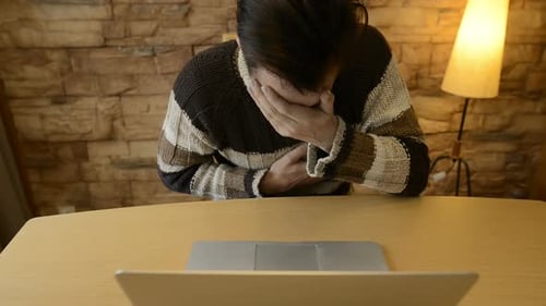 Young Adult Crying in Front of Laptop Computer