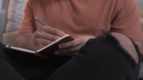 Adult Writing in Notebook at Home Close Up